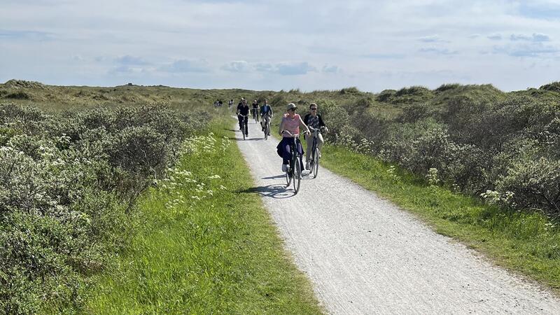 Bicyclists on road between vegetated dunes. © CWSS/ Bostelmann.
