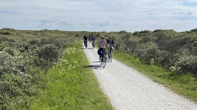 Bicyclists on road between vegetated dunes. © CWSS/ Bostelmann.